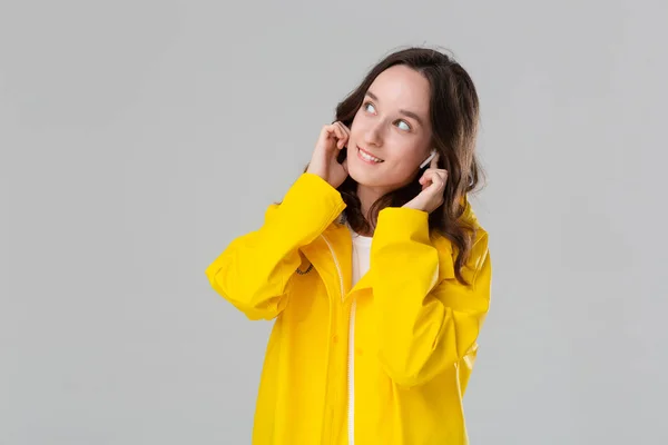 Chica morena vistiendo impermeable amarillo bailando escuchando música con auriculares inalámbricos. Concepto de disfrutar de la vida . — Foto de Stock