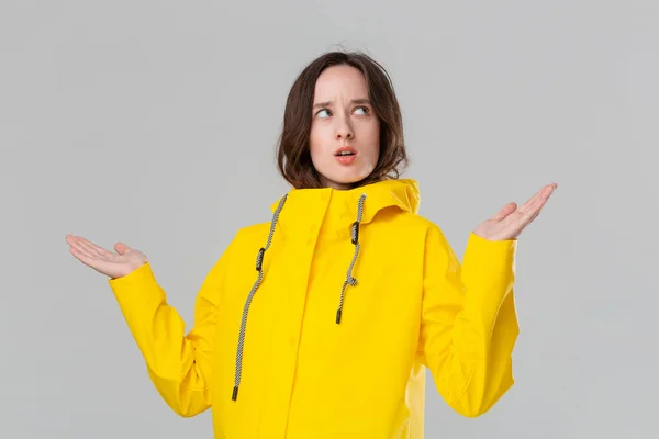 Chica morena bonita conseguir vestidos en impermeable amarillo y comprobar si la lluvia ha comenzado. Prepárate para el mal tiempo . —  Fotos de Stock