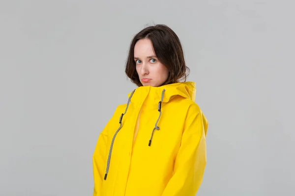 黄色のレインコートを着た悲しいブルネットの女の子。悪天候の準備をしろ. — ストック写真