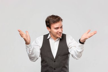 Beyaz gömlekli ve gri yelekli genç işadamı omuzlarını silkip şaşkınlık duygularını dile getiriyor..