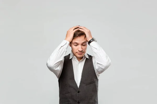 Hombre en una camisa blanca y gris chaleco embragues cabeza porque se enfrenta a algunos problemas necesitan ser abordados . — Foto de Stock
