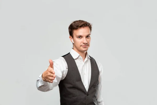 Joven hombre de negocios en una camisa blanca y chaleco gris está listo para estrechar la mano y comenzar un exitoso proyecto empresarial . — Foto de Stock