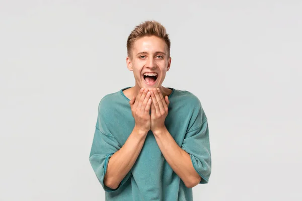 Spännande stilig ung man i en grön t-shirt som uttrycker känslor av lycka. — Stockfoto