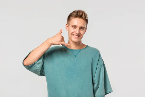 Adolescente bonito em uma camiseta verde de mãos dadas em um gesto de chamada . — Fotografia de Stock