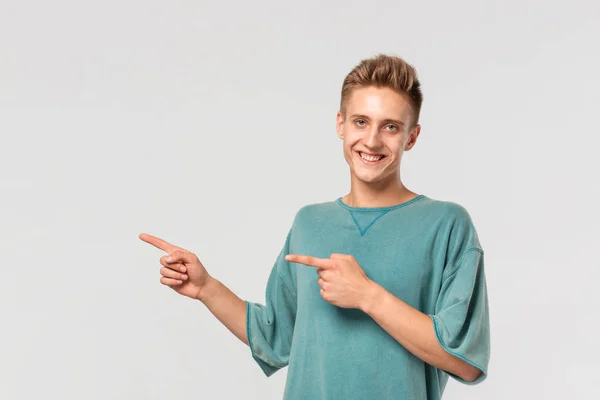 Όμορφος νεαρός σε ένα πράσινο μπλουζάκι δείχνει με τα δάχτυλά του αριστερά στο κενό χώρο για τη διαφήμιση. — Φωτογραφία Αρχείου