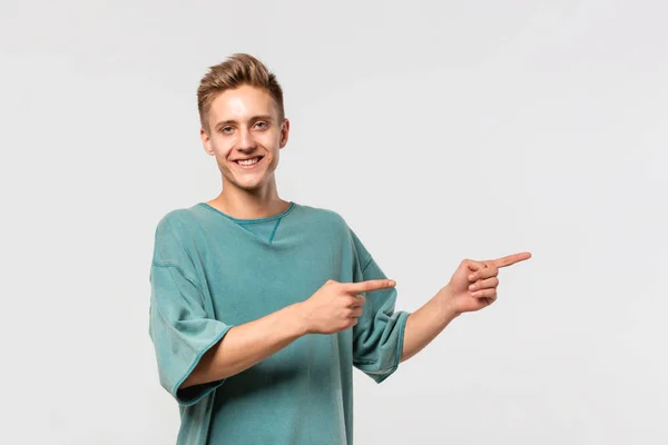 Красивый молодой человек в зеленой футболке показывается пальцами прямо на пустом месте для рекламы . — стоковое фото