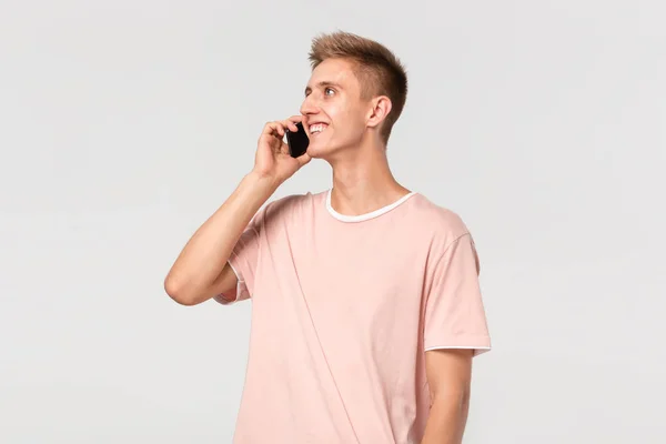 Ganska blond tonåring i en rosa t-shirt leende talar i telefon. — Stockfoto