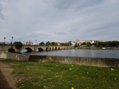 The historic granite Old Bridge crosses the Tua River in Mirandela, Portugal, with the cityscape and iconic tower behind. This scenic pedestrian landmark blends heritage and beauty in northern Portugal.