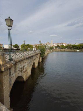 The historic granite Old Bridge crosses the Tua River in Mirandela, Portugal, with the cityscape and iconic tower behind. This scenic pedestrian landmark blends heritage and beauty in northern Portugal.