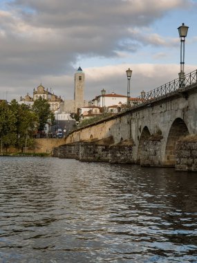The historic granite Old Bridge crosses the Tua River in Mirandela, Portugal, with the cityscape and iconic tower behind. This scenic pedestrian landmark blends heritage and beauty in northern Portugal.