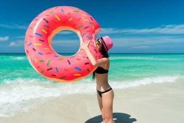 Pembe şapkalı güzel esmer kadın büyük şişme tüp bir ısırık Karayip Denizi sahilinde yaz güneşli bir günde alır