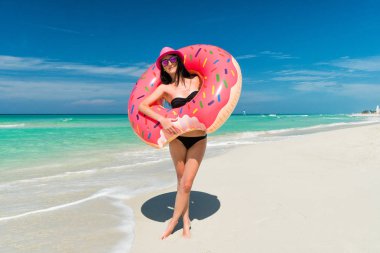 Gülümseyen güzel esmer kadın pembe şapkalı büyük şişme tüp Karayip Denizi Sahili içinde yaz güneşli gün duruyor