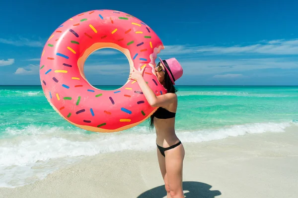 Pembe şapkalı güzel esmer kadın büyük şişme tüp bir ısırık Karayip Denizi sahilinde yaz güneşli bir günde alır