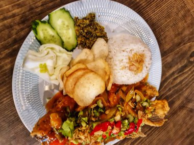 Baharatlı kızarmış balık, pilav, sebze ve patates kızartması ile birlikte dekoratif bir tabakta servis edilir. Asya mutfağını sergilemek için mükemmeldir..