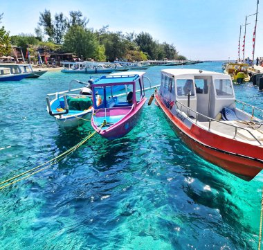 Lombok, Endonezya 5 Ağustos 2024. Gili Trawangan. Çarpıcı turkuaz su, tropik bir cennetteki renkli tekneleri yansıtır. Seyahat broşürleri ya da yaz tatili planları için mükemmeldir..