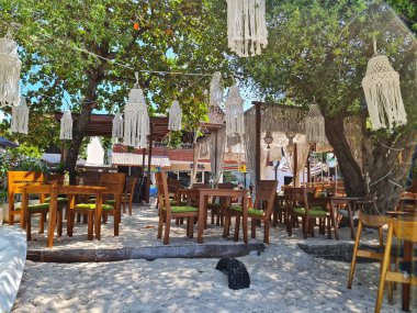 Lombok, Endonezya 5 Ağustos 2024. Gili Trawangan. Kumsaldaki açık hava restoranı ağaçlardan sarkan makrome lambalarla rahatlatıcı bir yemek alanı sağlar. Konukseverlik ve seyahat temaları için birebirdir..