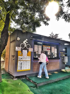 Seul, Güney Kore, 11 Kasım 2024. Bir kadın güneşli bir günde bisiklet kiralama standında bisiklet kiralıyor. Seyahat blogları ve şehir macerası içeriği için ideal..