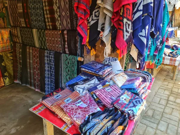 Lombok, Endonezya 5 Ağustos 2024. Parlak renkli dokuma kumaşlar ve tekstil ürünleri Lombok 'taki açık bir pazarda sergileniyor. Seyahat ve kültürel ürün tanıtımı için mükemmel..