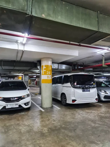 Jakarta, Endonezya 12 Nisan 2025. Arabalar bir yeraltı otoparkında sarı bir destek sütunu ile, şehir içi bir manzara yaratıyor şehir yaşam tarzı içeriği için harika.