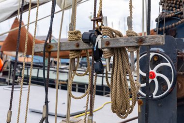 Ahşap bir direkte bulunan deniz halatları ve makaraların detaylı görünümü, denizcilik ortamında yelken donanımının işçiliğini ve işlevselliğini vurguluyor.