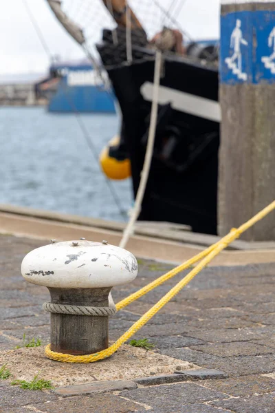 Limanda sarı halatla demirlemek, arka planda bulanık gemi, deniz altyapısını ve kıyı ortamındaki deniz elementlerini vurgulamak