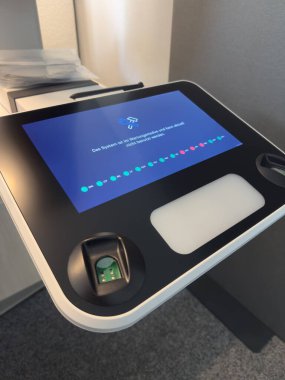 Melle, Almanya - 31 Ağustos 2025: Biyometrik veri bilgisayarı dokunmatik ekran arayüzü ve parmak izi tarayıcısıyla gelişmiş teknolojiyi ve parlak bir ortamda güvenli erişimi vurguluyor