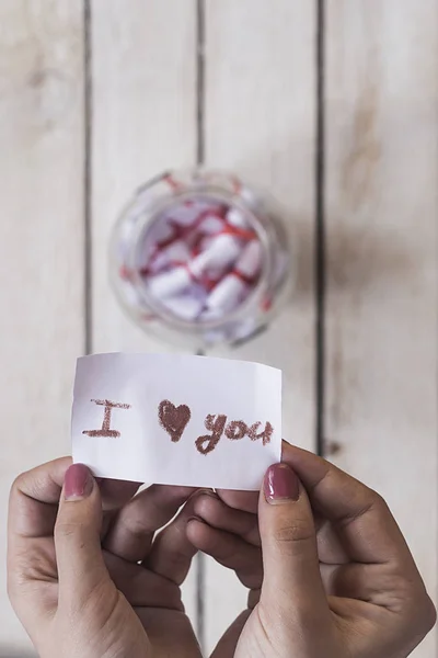 I Love you text on rolled paper. Female opening a gift glass jar with wishes and desires. A gift from her lover