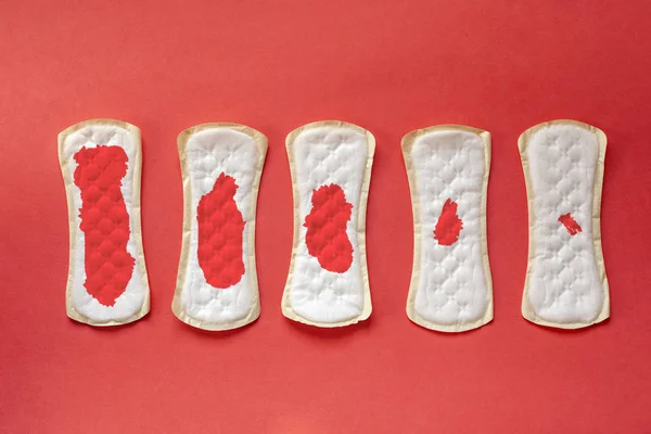 Weibliche Hygienepolster mit Blut über Tage auf rotem Hintergrund — Stockfoto