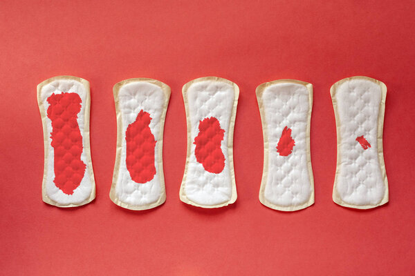 Feminine hygiene pads with blood during period days on red background