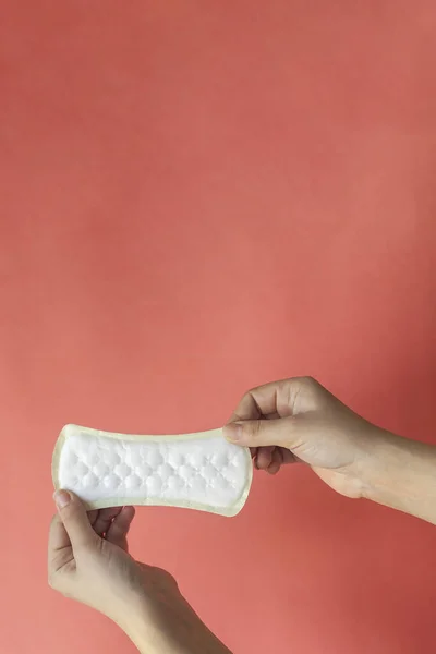 A white sanitary pad in woman's hands on a pink background with copy space. Absorbent item for women special days. Hygiene and health concept. — Stock Photo, Image