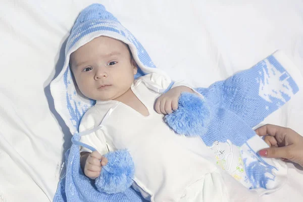 Όμορφο νεογέννητο μωρό σε λευκό κρεβάτι με λευκό φόντο φορώντας μπλε καπέλο ή ύφασμα — Φωτογραφία Αρχείου