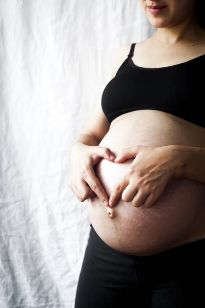 Těhotná žena 9. měsíc srdíčku s rukama — Stock fotografie