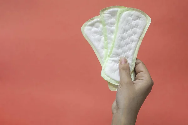 Manos de mujer sosteniendo almohadillas de higiene femenina. Las manos de la hembra sostienen almohadillas menstruales o toallas sanitarias para las mujeres —  Fotos de Stock