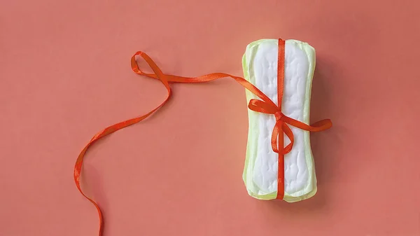 En stack av bindor eller menstruationsprodukter pads bundna med ett rött band på en rosa bakgrund. Kritiska dagar, intim, perioden dagar koncept — Stockfoto