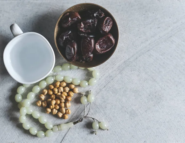 Rosario, permen Iftar dan buah-buahan kering dengan secangkir air. Lihat dari atas. Foto lay datar — Stok Foto