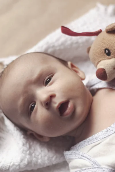 2 maand babyjongen liggen. Close-up van schattige schattige pasgeboren babyjongen van twee maanden op zacht textiel. Mooie kind spelen met pluche speelgoed — Stockfoto