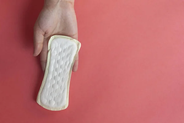 Manos de mujer sosteniendo una almohadilla de higiene femenina. Las manos de la hembra sostienen almohadillas menstruales o toallas sanitarias para las mujeres — Foto de Stock