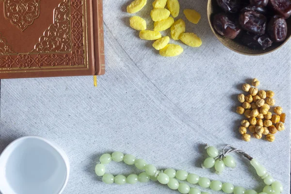 Al-Qur 'an, Rosario, permen Iftar dan buah-buahan kering dengan secangkir air. Lihat dari atas. Foto lay datar — Stok Foto