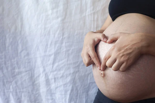 Mujer embarazada al noveno mes mostrando el corazón con las manos — Foto de Stock