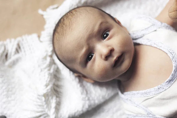 2个月男婴撒谎。两个月可爱可爱的新生男婴特写镜头。带着可疑面孔的婴儿。严肃的小孩儿童的情感发展. — 图库照片