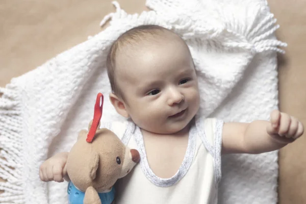2 maand babyjongen liggen. Close-up van schattige schattige pasgeboren babyjongen van twee maanden op zacht textiel. Mooie kind spelen met pluche speelgoed — Stockfoto