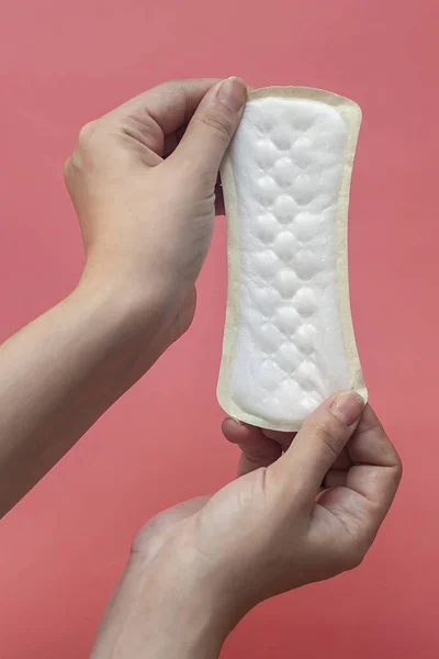 A white sanitary pad in woman's hands on a pink background with copy space. Absorbent item for women special days. Hygiene and health concept. — Stock Photo, Image