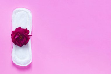 Üzerinde kırmızı gül olan hijyenik peçete. Parlak pembe arka planda. Kadınadet döngüsünü gösteren dönem günleri kavramı.