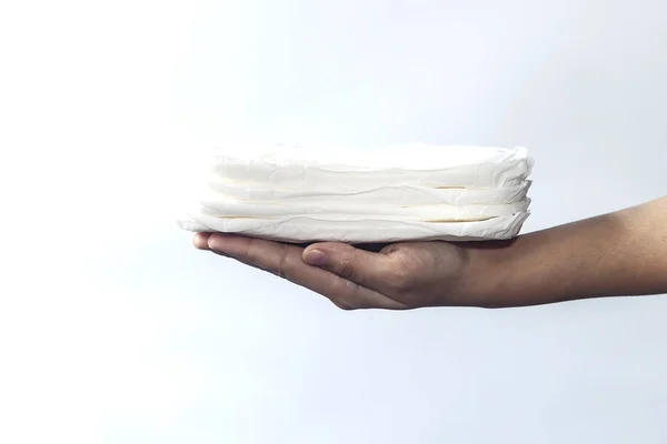 Die Hand der Frau hält einen Stapel Damenbinden vor weißem Hintergrund. Konzept der Periode Tage zeigt weiblichen Menstruationszyklus. — Stockfoto