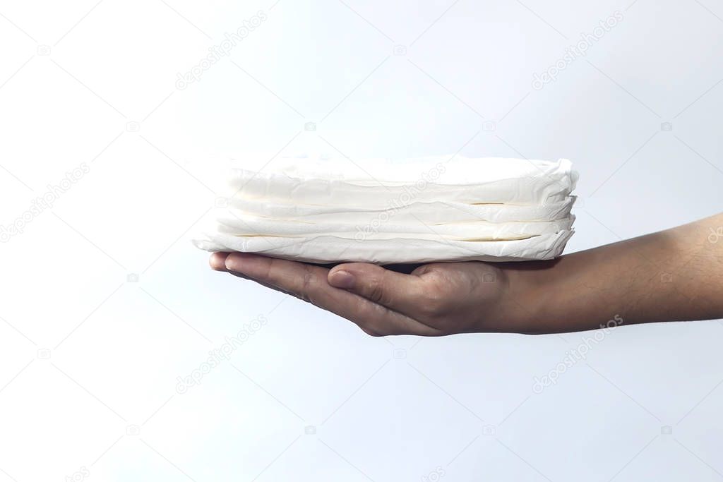 Woman's hand holding a stack of sanitary napkins against white background. Period days concept showing feminine menstrual cycle.