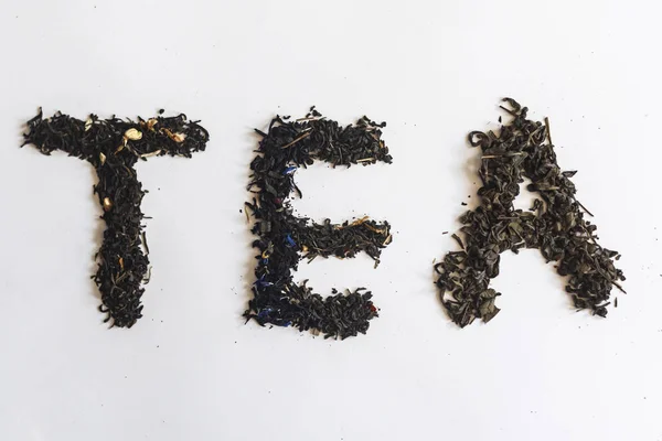 Das Wort Tee mit trockenen Teeblättern — Stockfoto