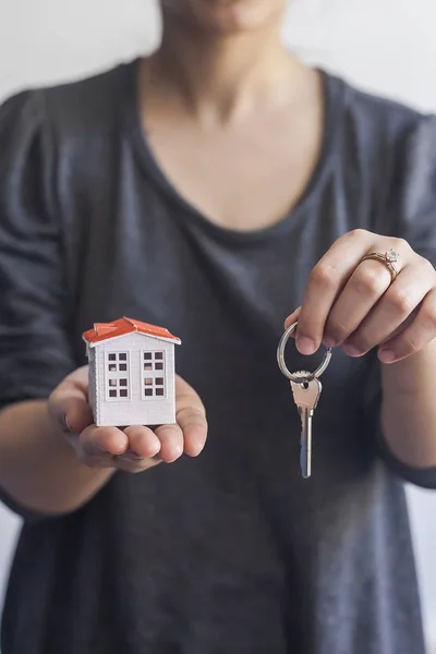 Woman holding miniature toy house and keys. Real estate agent holding keys and toy house. Buying or selling real estate — 스톡 사진