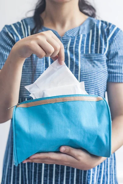 Young women taking sanitary pads inside of her cosmetic bag on blue background — Stock Photo, Image