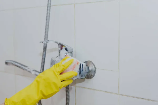 Ama de casa limpieza grifo de baño y ducha Grifo. Mucama en guantes protectores amarillos lavando grifo de baño sucio. Las manos de la mujer baño de lavado — Foto de Stock