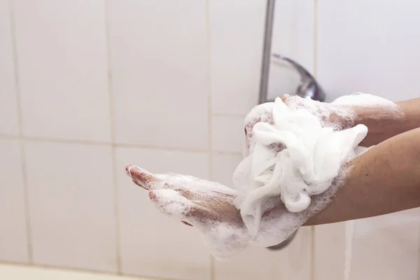 Mujer lavándose las manos con una esponja en el baño. Brazos de lavado femeninos con una esponja espumosa en el baño. Cuidado corporal y concepto limpio — Foto de Stock